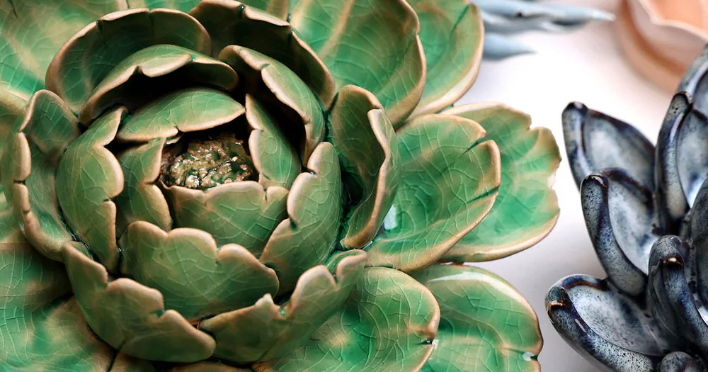 Close-up of a green ceramic succulent plant with other decorative plants in the background.