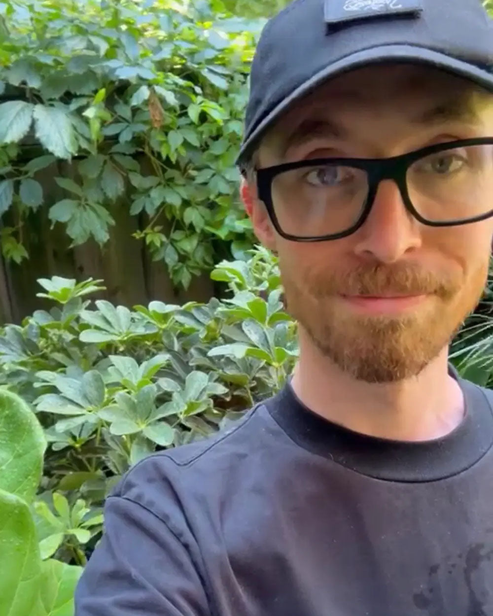 Chive Studio plant shop manager Ryan taking a selfie in front of green plants.
