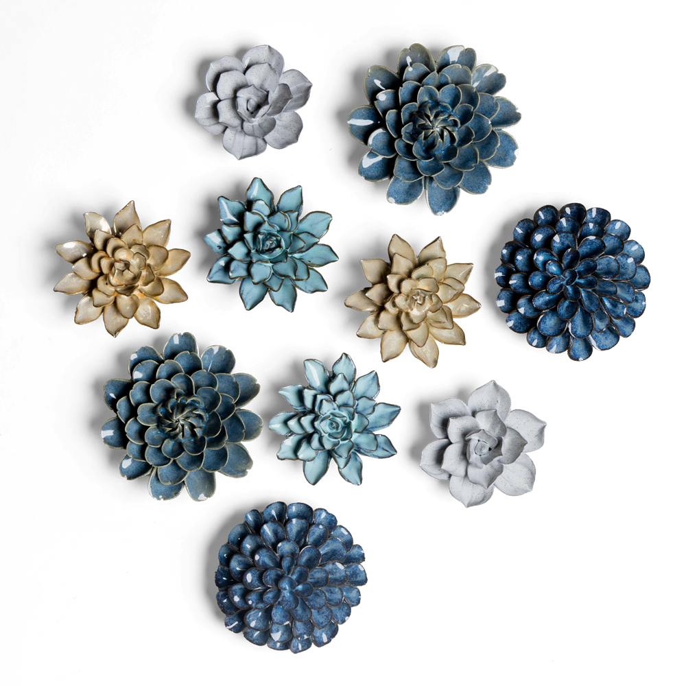 A collection of decorative wall flowers in various styles and shades of blue, gold, and white, arranged on a black background. Each flower has unique petal shapes and textures.