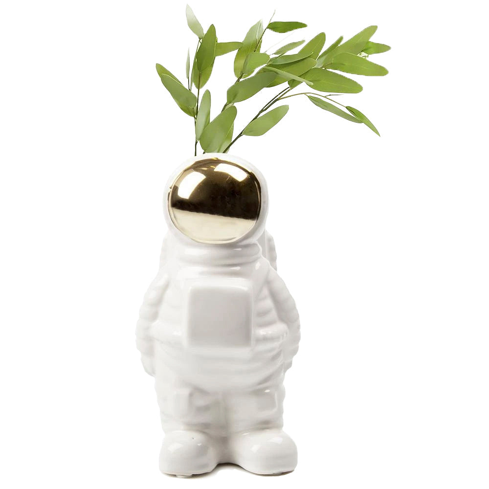 Astronaut Ceramic Unique Flower Vase from Chive Studio 2024, in the shape of a cartoon-style astronaut, with a shiny golden helmet and green leaves sprouting from the top, isolated on a white background, commemorating the first man in space.