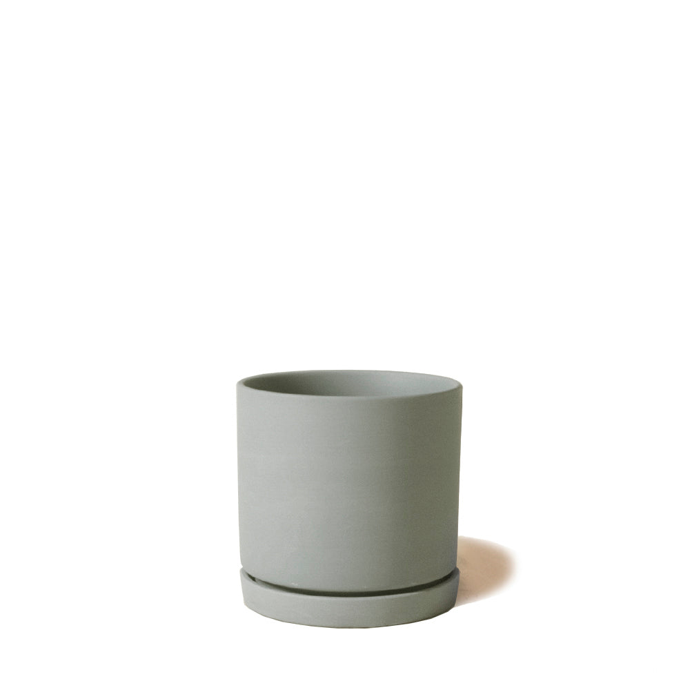 A simple gray Dojo Porcelain Modern Indoor Plant Pot with Saucer, from the Chive Studio 2024, with a smooth finish and matching saucer, isolated on a white background.