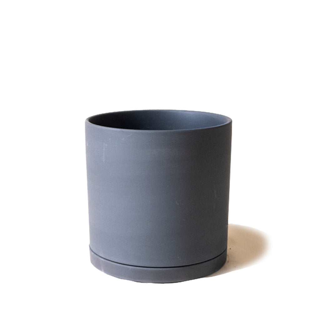 A simple gray Dojo Porcelain Modern Indoor Plant Pot with Saucer, from the Chive Studio 2024, with a smooth finish and matching saucer, isolated on a white background.