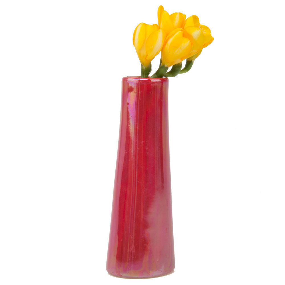A glossy, red Galaxy Ceramic Bud Vase For Flowers containing a small bouquet of vibrant yellow tulips against a plain white background by Chive Studio 2024.