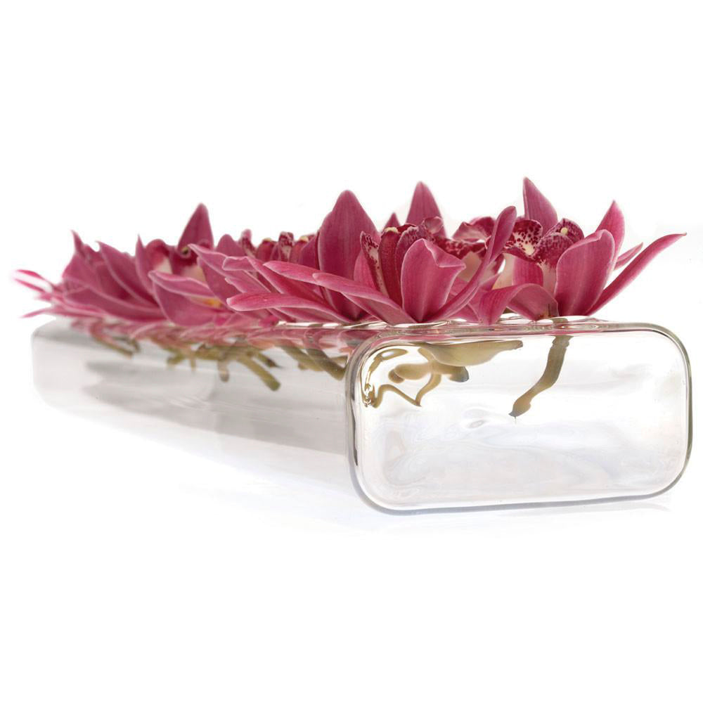 A Rectangle Flute Glass Modern Clear Flower Vase from Chive Studio 2024 lying horizontally, containing a row of vibrant pink lotus flowers known for their flower longevity, displayed against a white background.