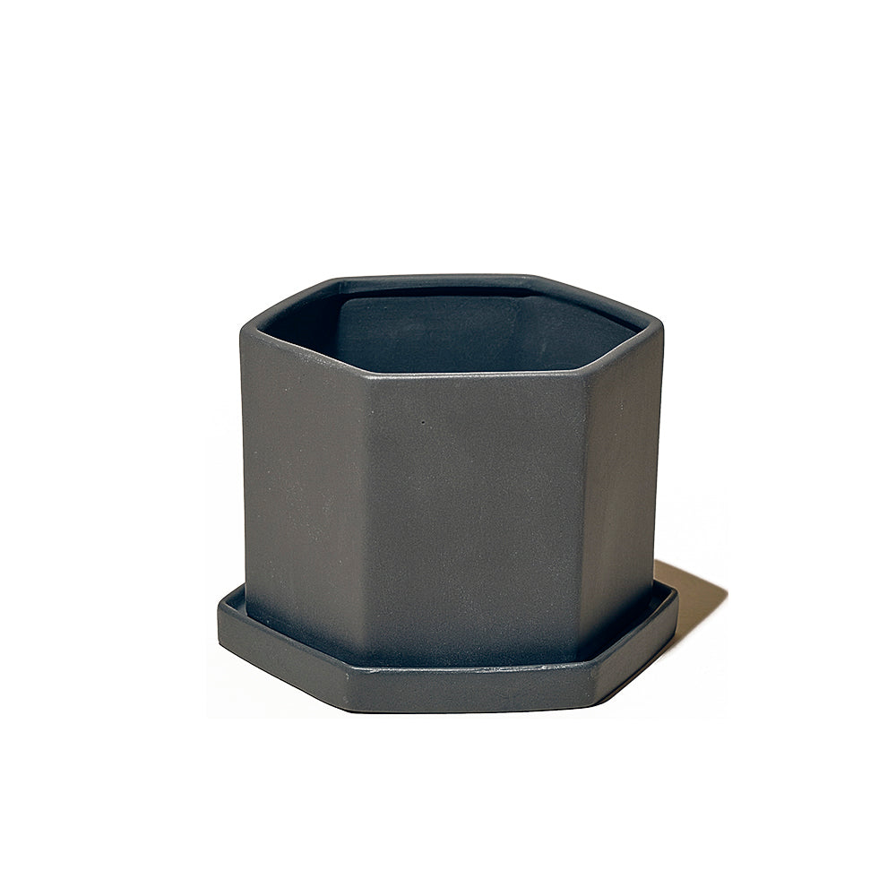 A Hexi Porcelain Pot With Drainage Hole, dark gray planter with a deep planting space, positioned on a matching hexagonal saucer against a white background.