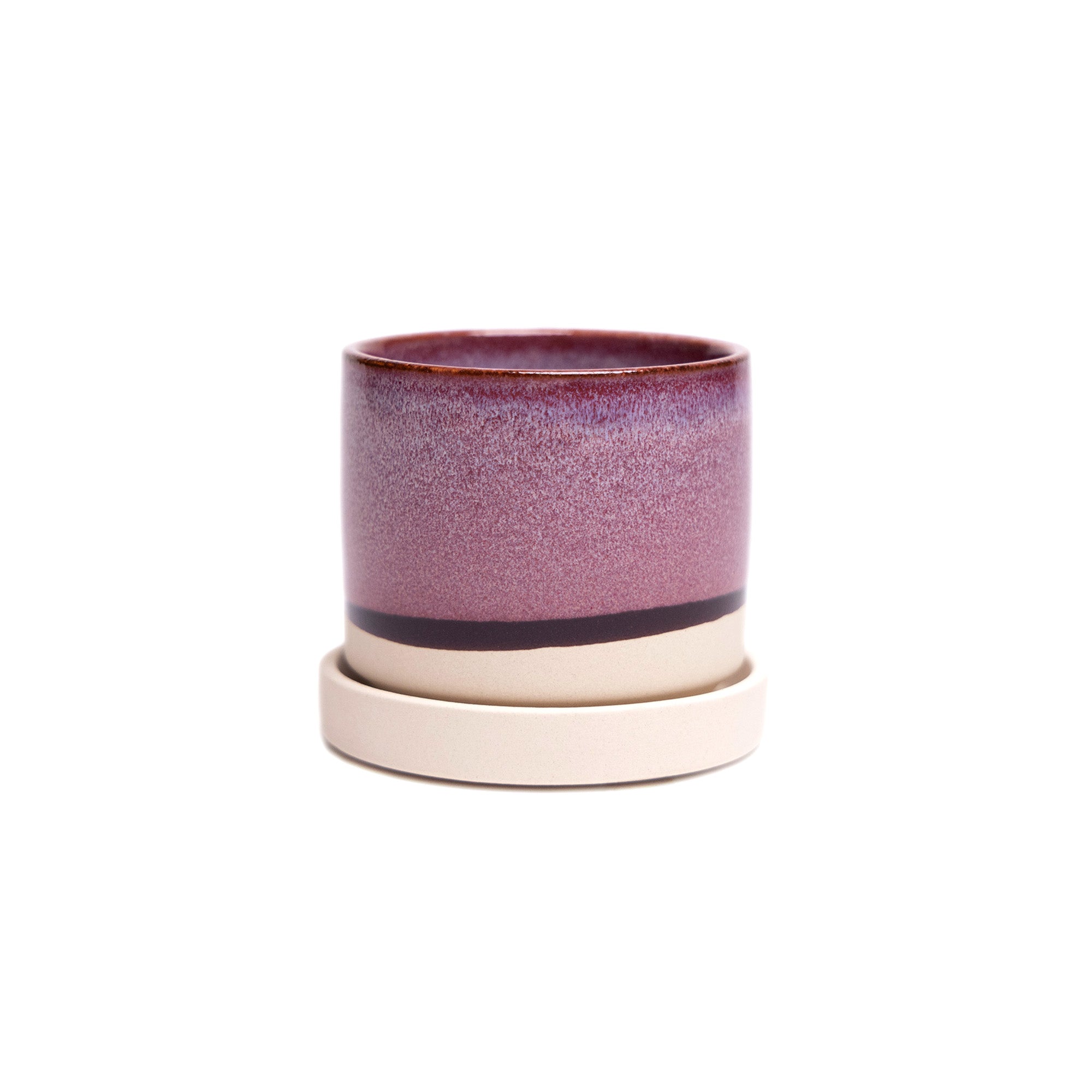 A Minute Ceramic Pot And Saucer Set With Drainage pot with an ombré design transitioning from deep lilac to light pink, separated by a horizontal black stripe, on a white isolated background. By Chive Studio 2024.