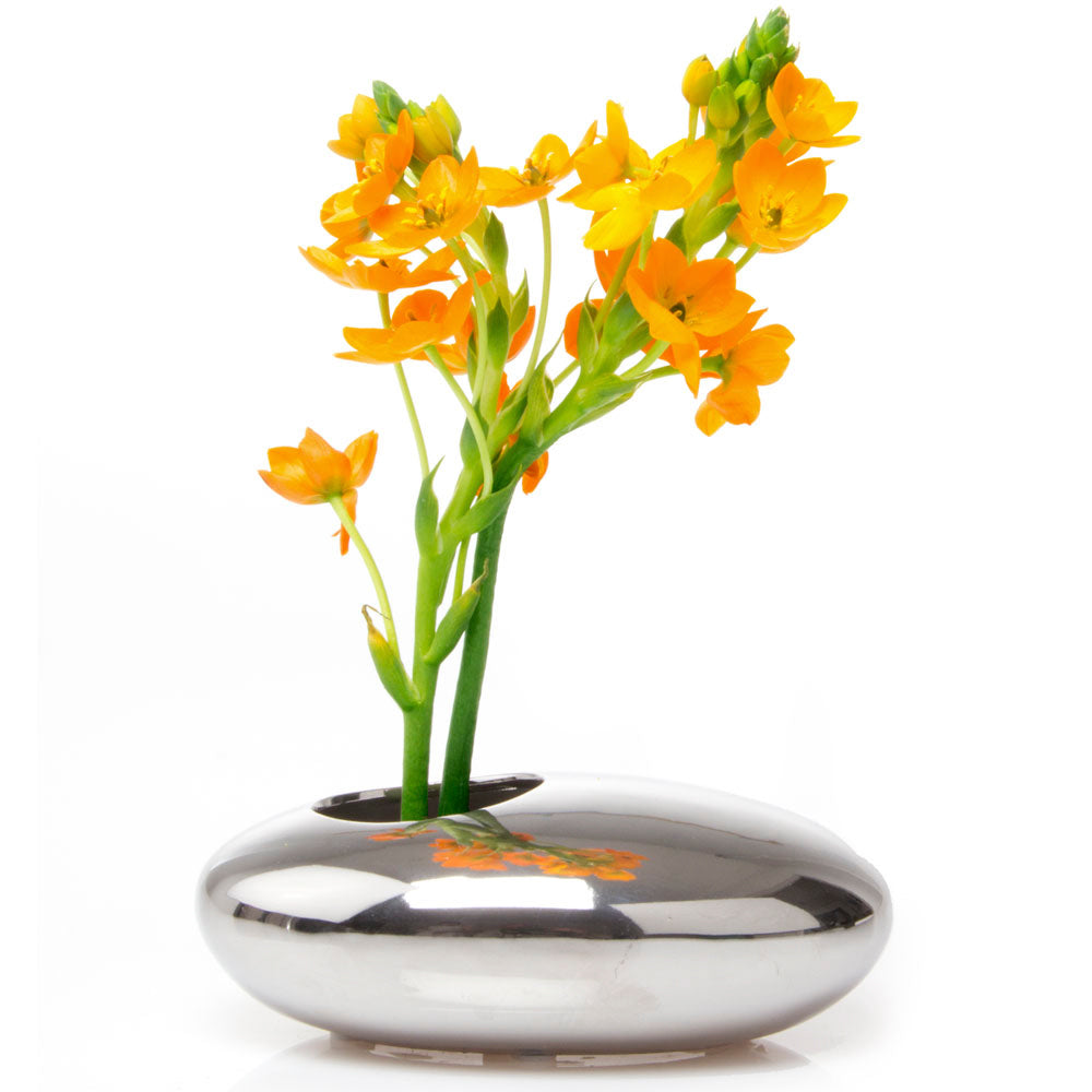 A small bouquet of vibrant orange flowers arranged in a Chive Studio 2024 Pebble Ceramic Ikebana Kenzan Container with a sleek, oval shape, isolated on a white background.