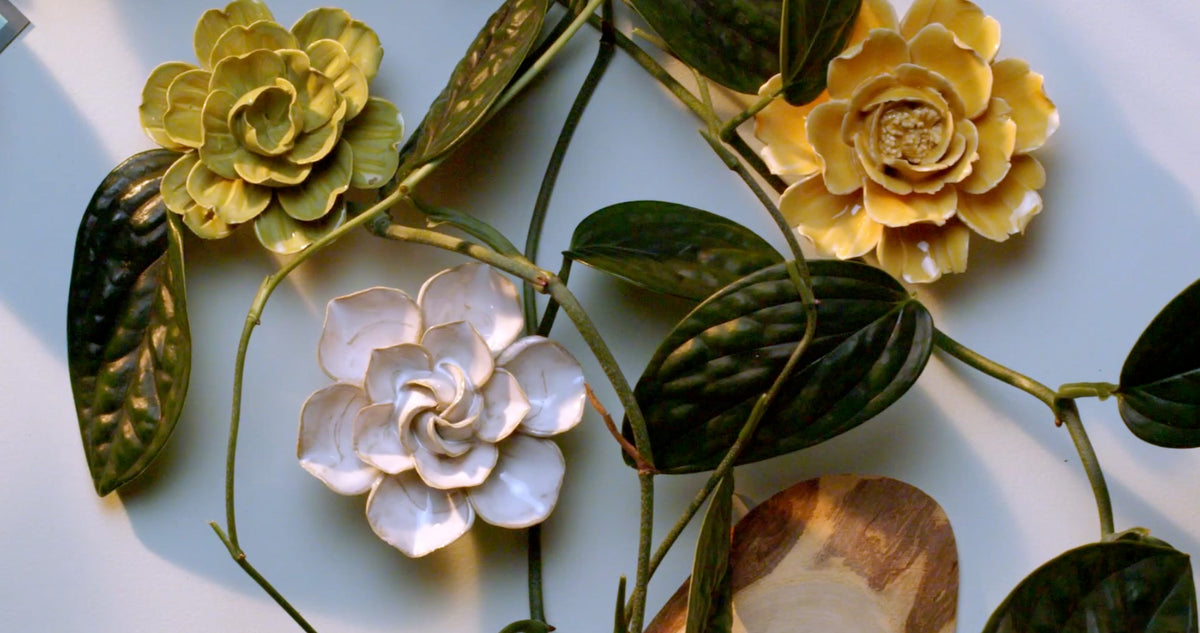 Top-down pan across a desk of ceramic flowers and monstera leaves — English garden style wall decor by Chive Studio