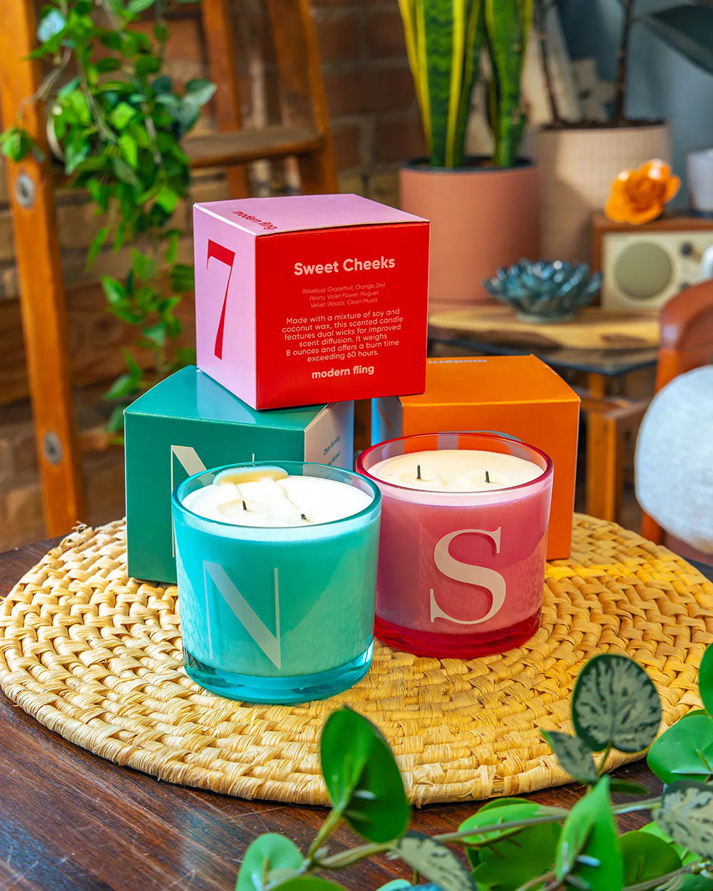 Two Chive Modern Fling teal nectar and pink sweet cheeks coconut soy medium candles styled with packaging boxed in a home setting.