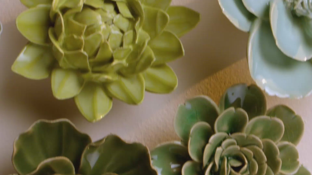 Green and yellow ceramic flowers composed top-down as one arrangement — curated wall art sets that arrive as a finished wall.